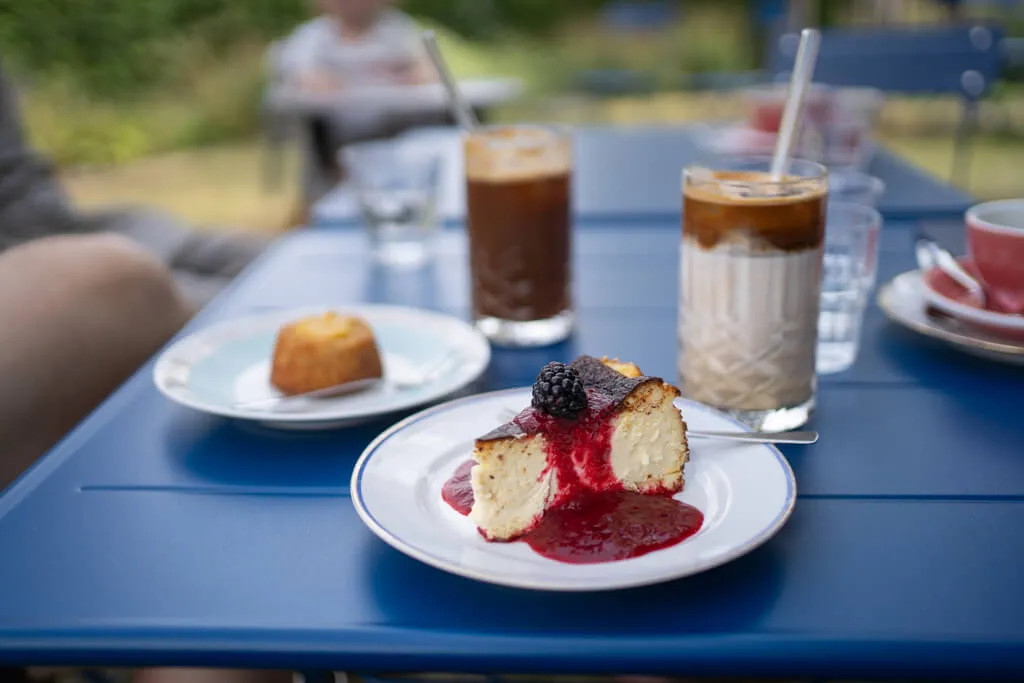 Baskischer Cheesecake und sommerliche Kaffeegetränke im Außenbereich des Cafés