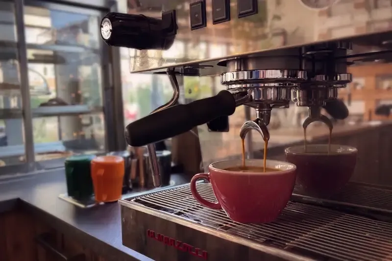Frisch gebrühter Espresso läuft aus der Siebträgermaschine in eine rote Tasse