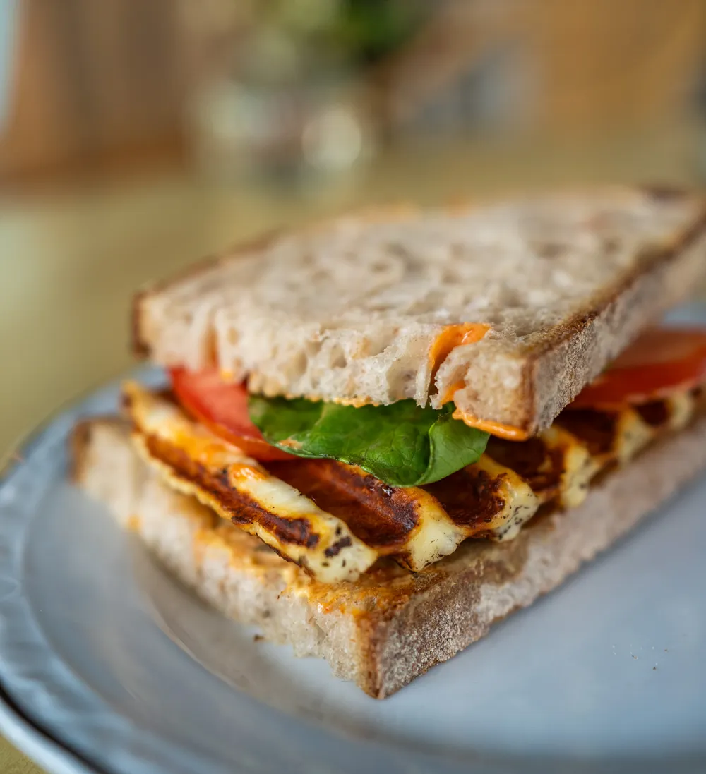Halloumi-Sandwich auf AuBacke-Sauerteigbrot mit Tomate und Spinat auf einem Teller